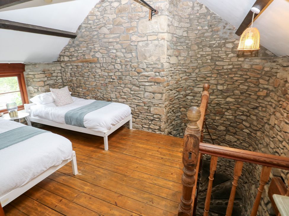 A bedroom with two beds and wooden stairs at Melyn in Aberdare