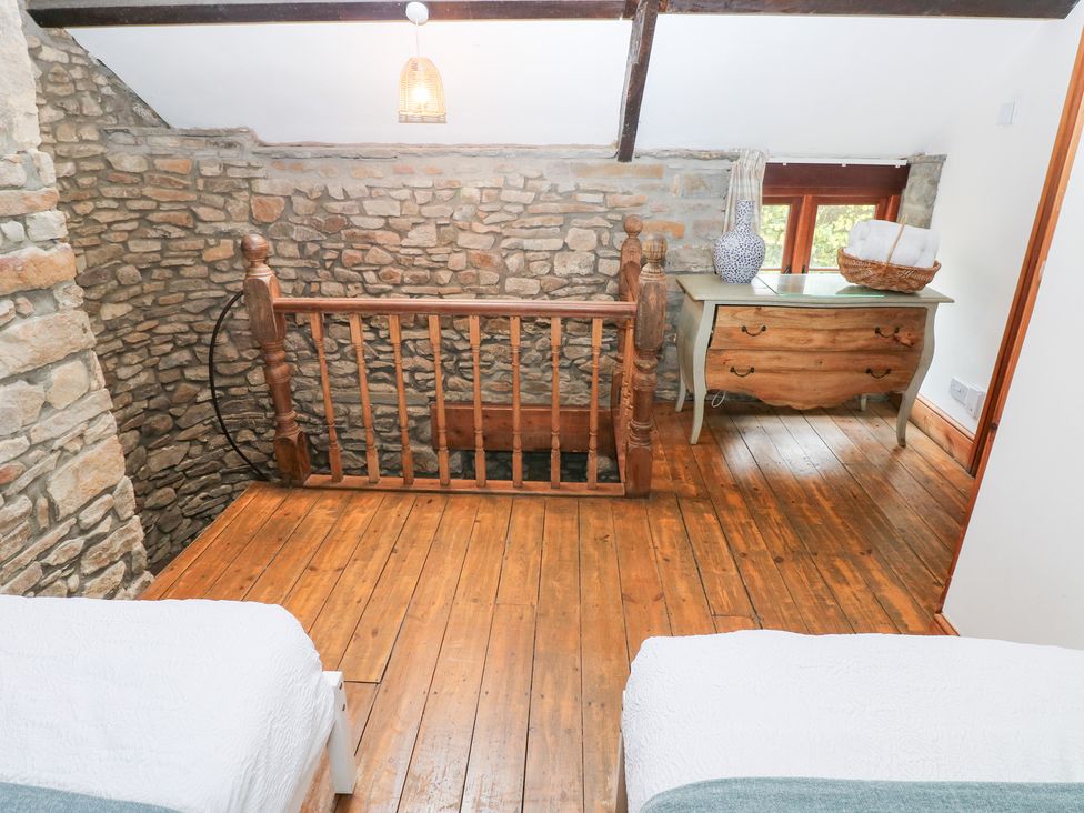 A bedroom with a stone wall and wooden flooring at Melyn in Aberdare