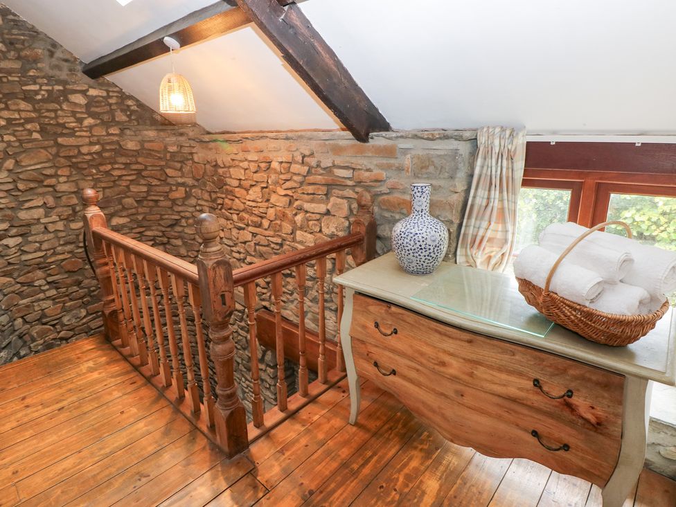 A staircase landing area with a stone wall and wooden railing at Melyn in Aberdare