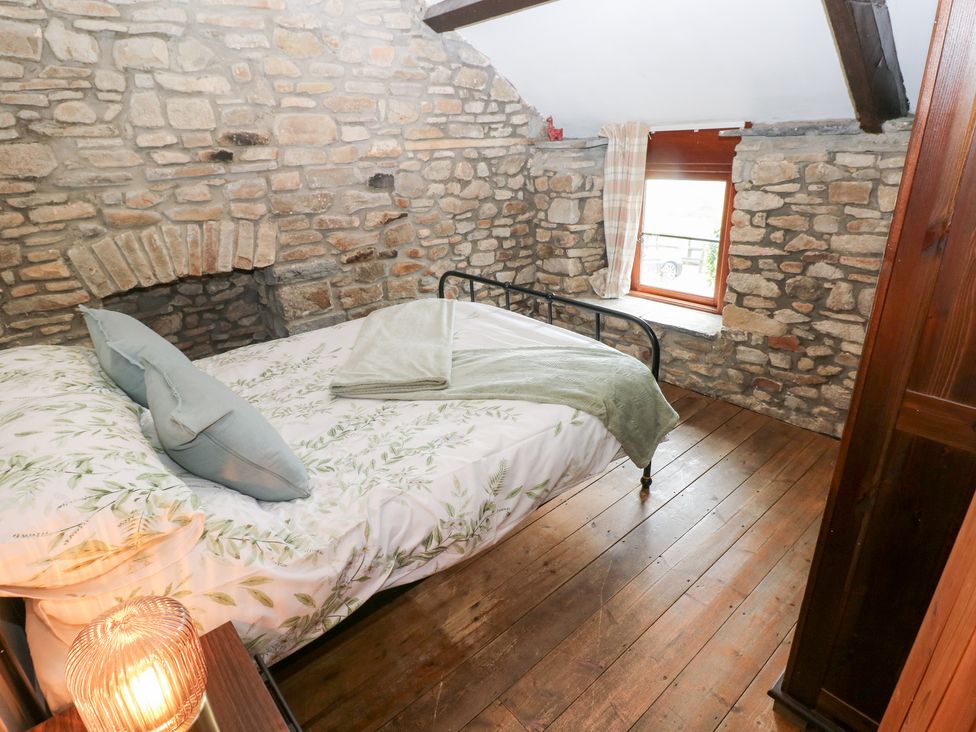 A bedroom with a bed and stone walls at Melyn in Aberdare