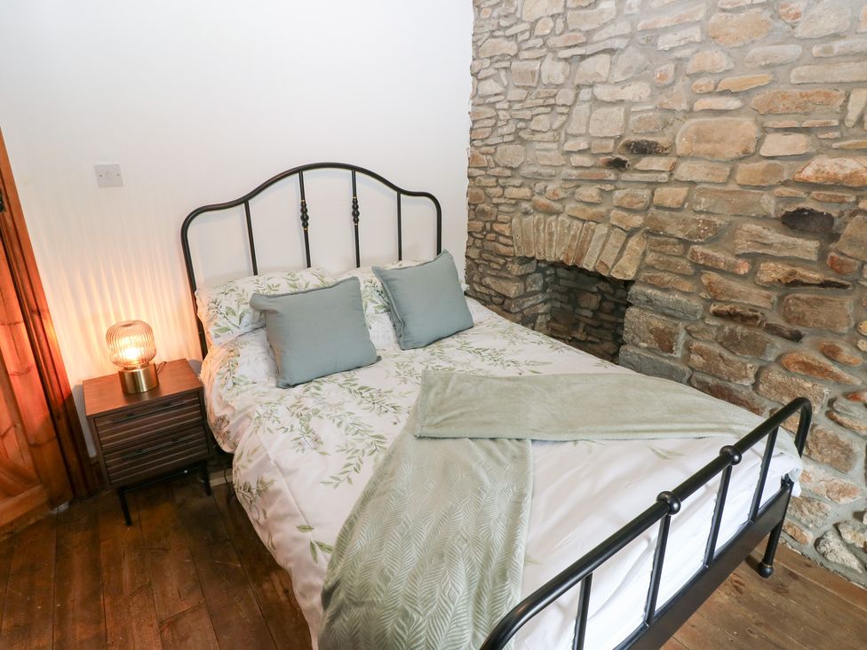 A bedroom with a bed and stone wall at Melyn in Aberdare