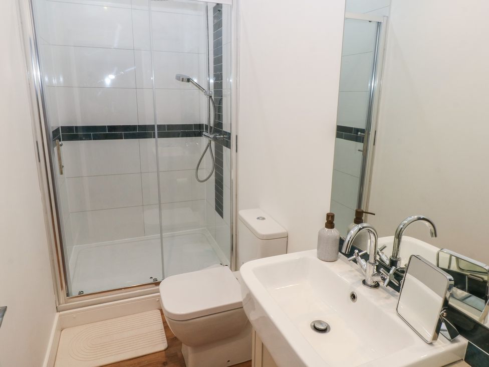 A bathroom with shower, toilet, sink and mirror at Awelfryn
