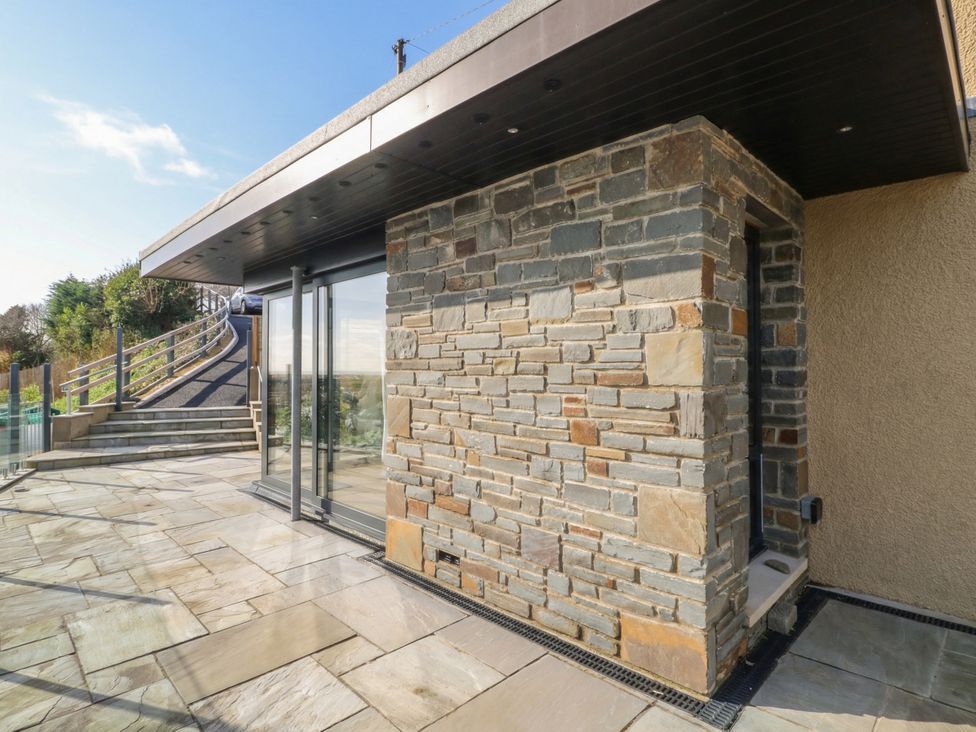 An outdoor area with stone wall and glass door at Awelfryn