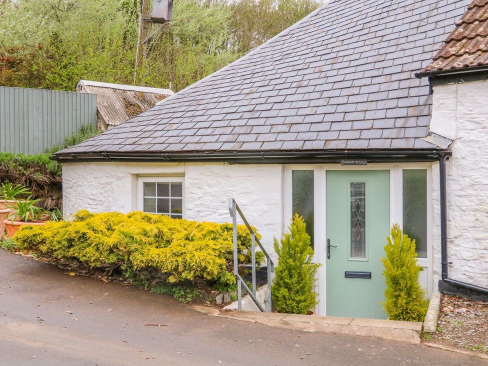 An entrance with a green door and shrubs at Round Barn in Ilfracombe
