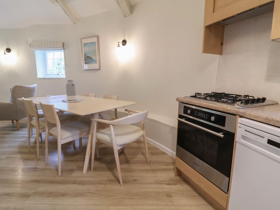 A kitchen with a dining table and chairs, stove, and oven at Round Barn in Ilfracombe
