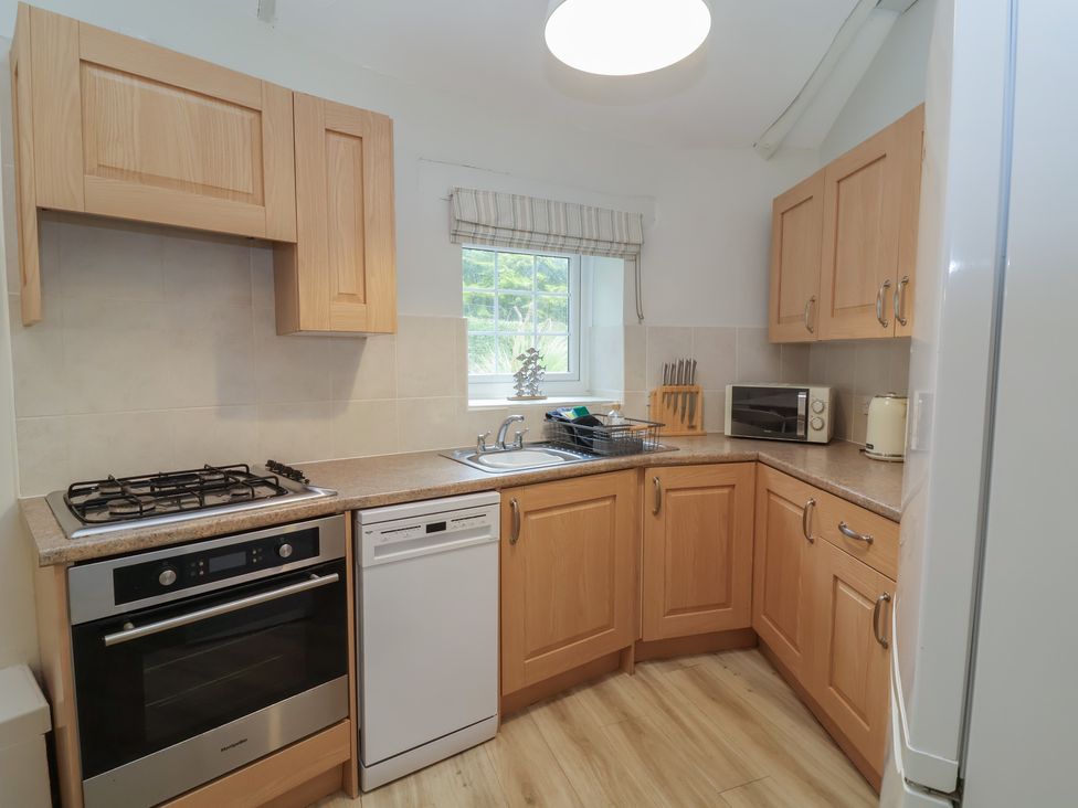 A kitchen with cabinets, sink, and oven at Round Barn in Ilfracombe