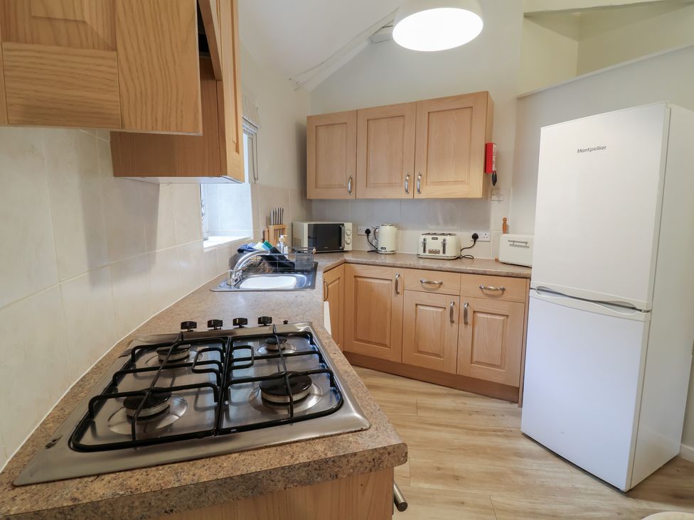A kitchen with cabinets and appliances at Round Barn in Ilfracombe