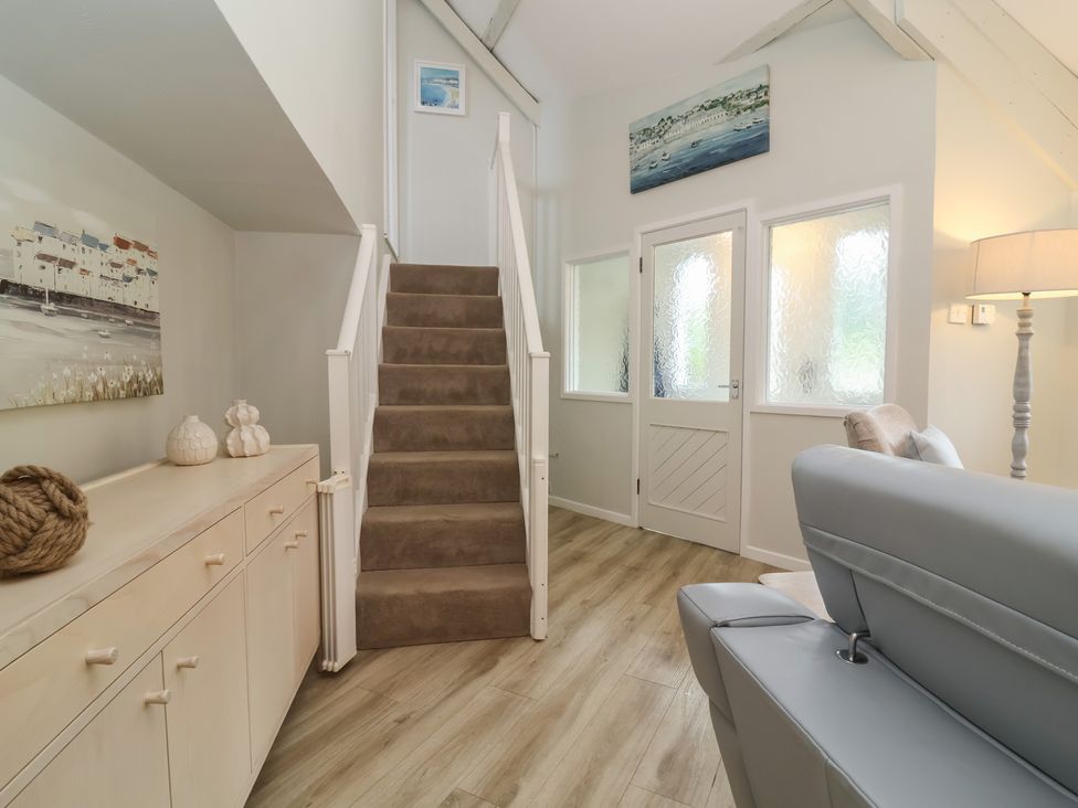 A hallway with a staircase and console table at Round Barn Ilfracombe