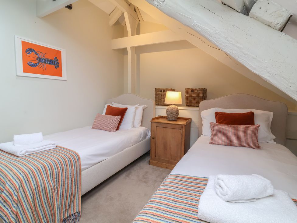 A bedroom with two single beds and a bedside table at Round Barn in Ilfracombe