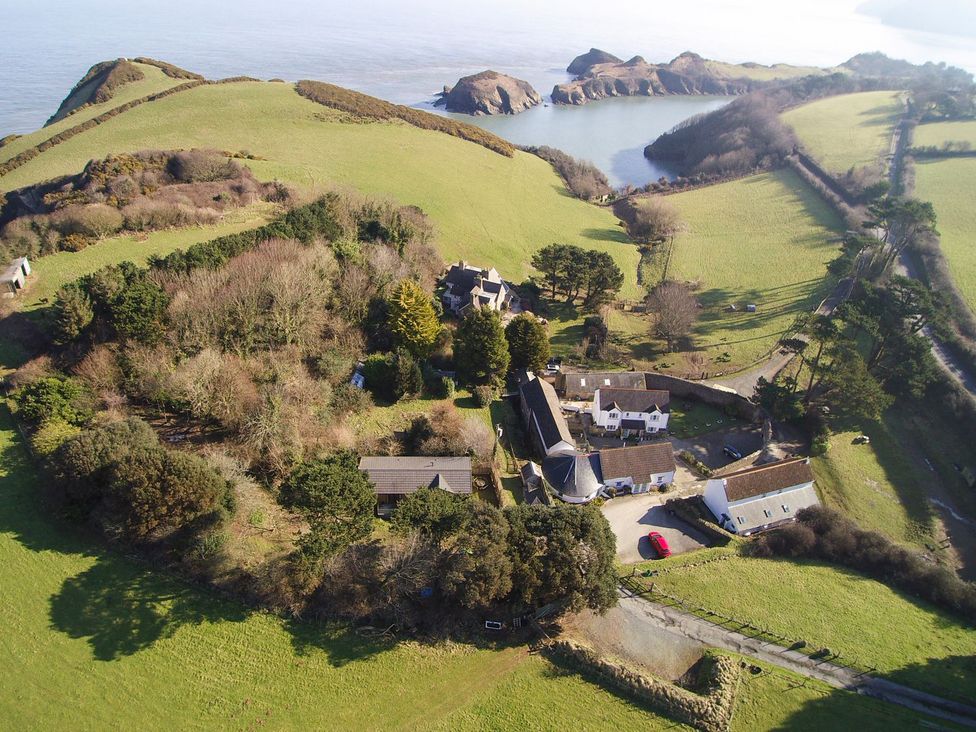 An aerial view of a property surrounded by greenery and water at Round Barn in Ilfracombe