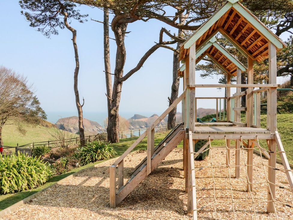 A playhouse with a slide and ladder overlooking the ocean at Round Barn in Ilfracombe