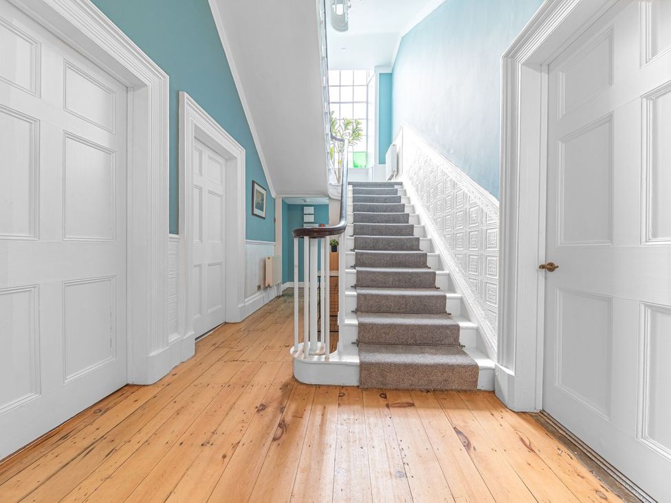 A hallway with stairs and doors at 8 Corkickle Whitehaven