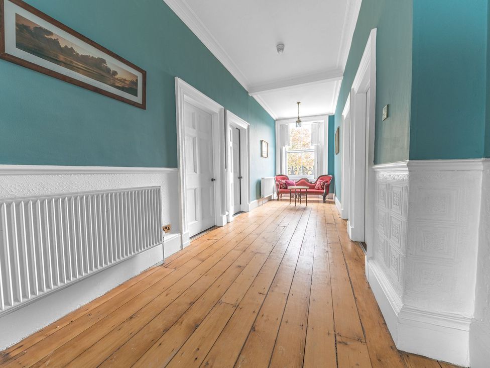 A hallway with wooden flooring and a chair at 8 Corkickle Whitehaven