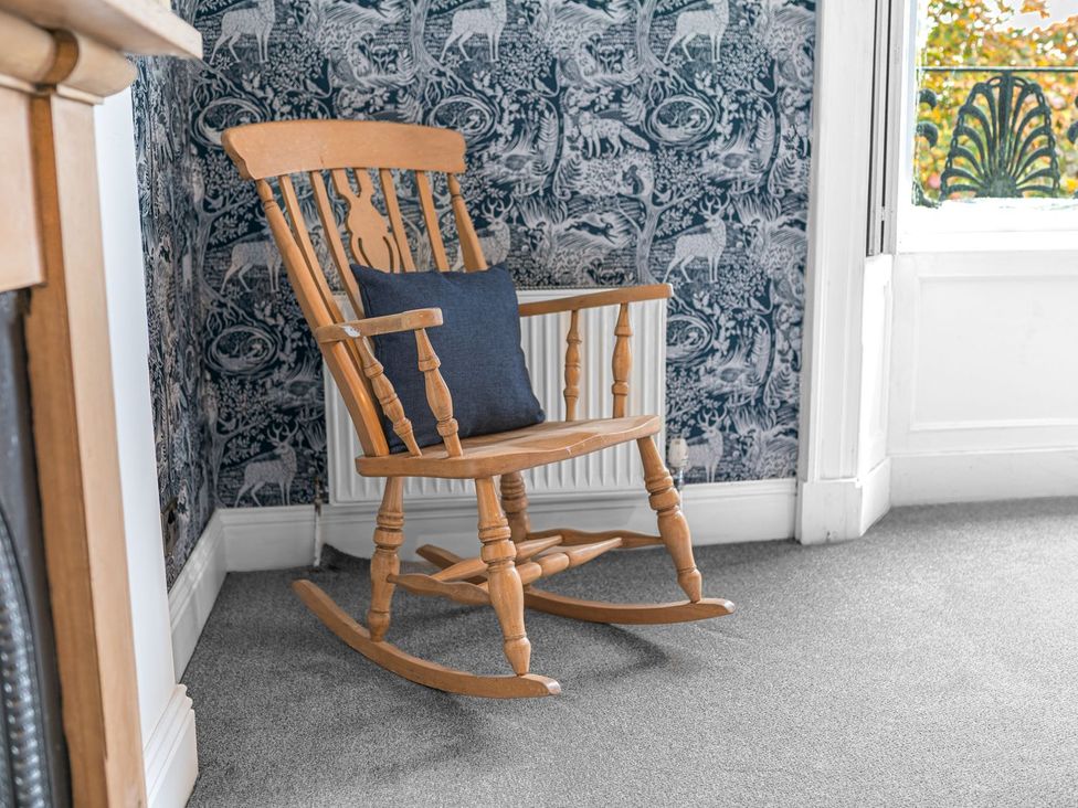 A rocking chair with a pillow next to a window at 8 Corkickle in Whitehaven