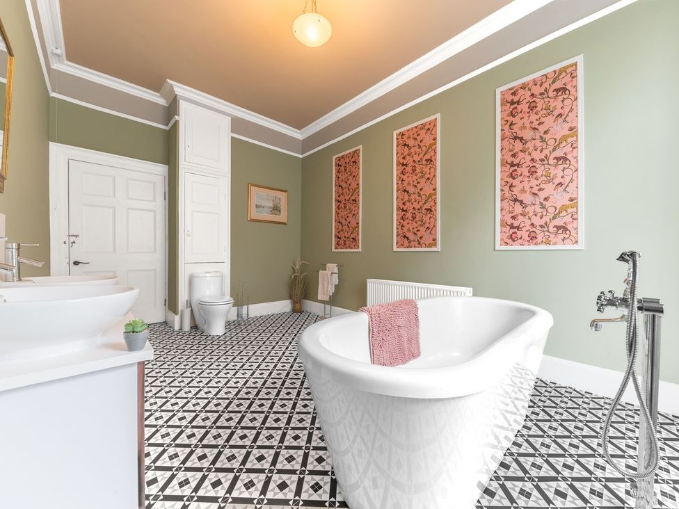 A bathroom with a bath tub, toilet, sink, and wall art at 8 Corkickle in Whitehaven