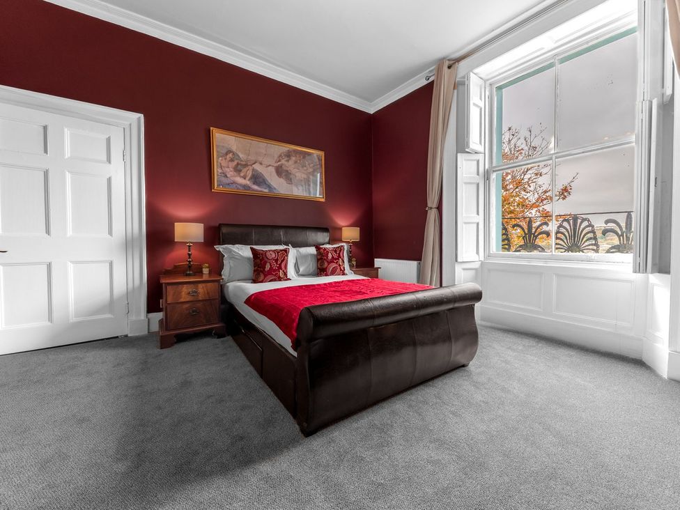 A bedroom with a bed, lamp, and window at 8 Corkickle in Whitehaven