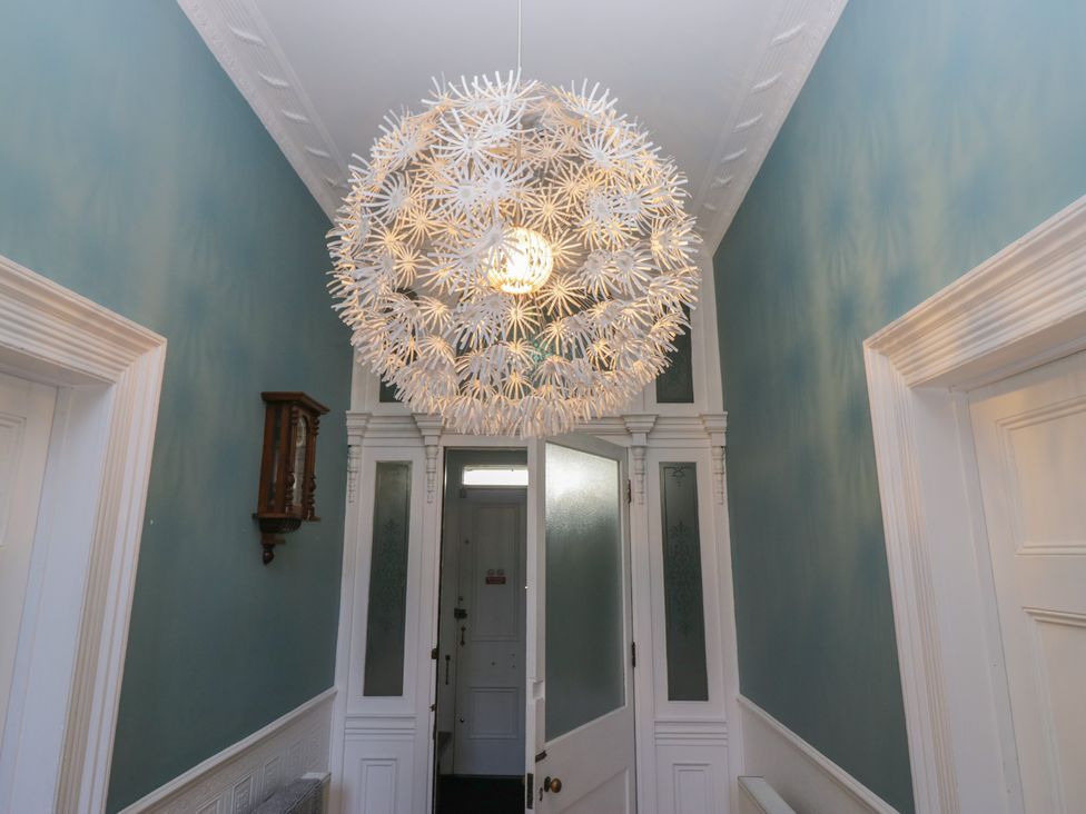 A hallway with a chandelier and doorframes at 8 Corkickle Whitehaven