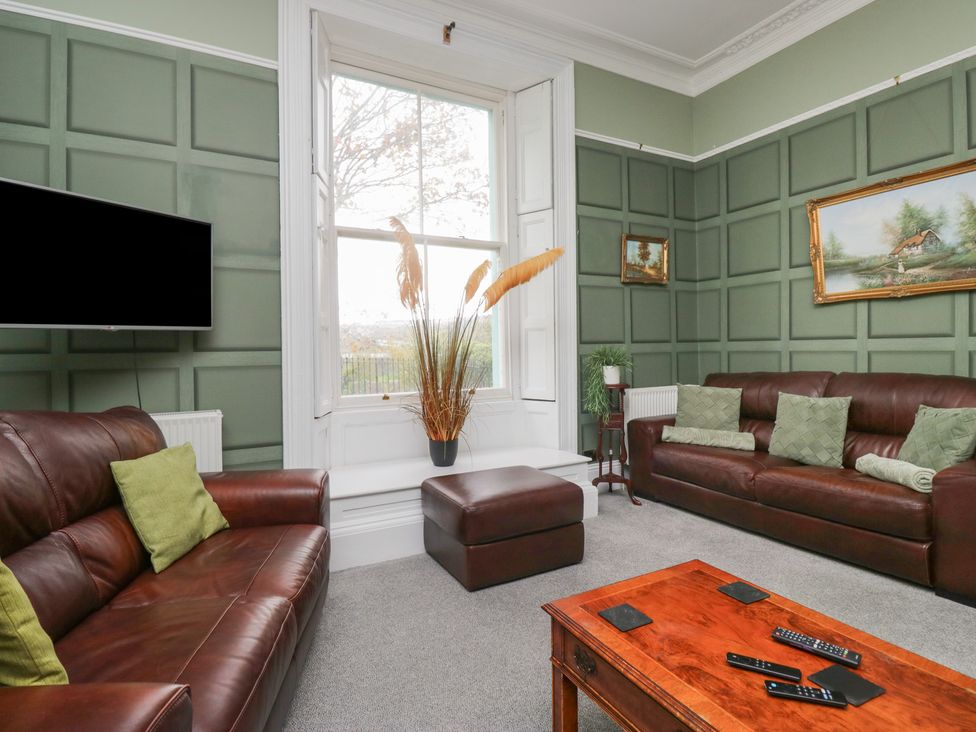 A living room with brown sofas and a television at 8 Corkickle in Whitehaven