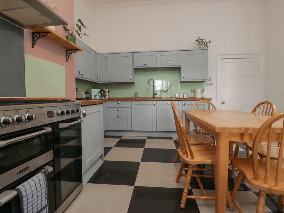 A kitchen with cabinets and a dining table at 8 Corkickle Whitehaven