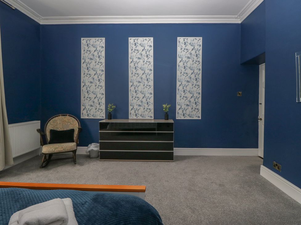 A bedroom with an armchair and dresser at 8 Corkickle Whitehaven
