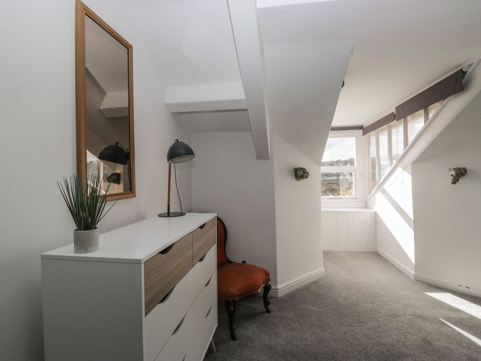 A room with a mirror, lamp, dresser, and armchair at 8 Corkickle, Whitehaven