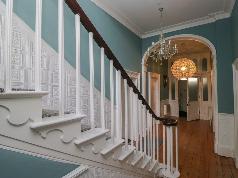 A staircase and chandelier in a hallway at 8 Corkickle in Whitehaven