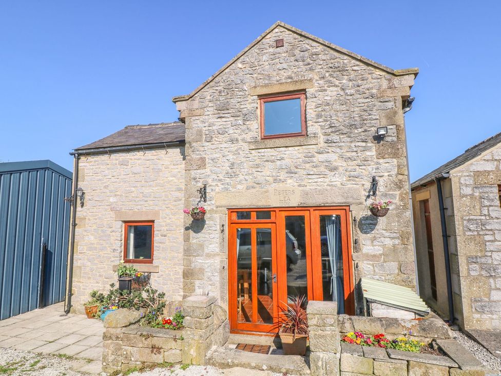 A stone house with a front door and flower pots at Peters Lea in Bakewell