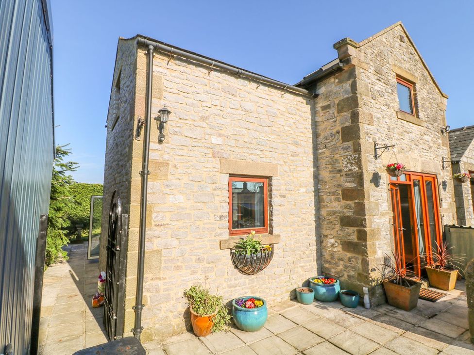 An outdoor area with stone wall, windows, planters and paved area at Peters Lea, Bakewell