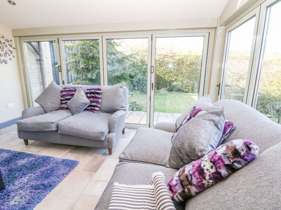A conservatory with a sofa and garden view at Peters Lea Bakewell