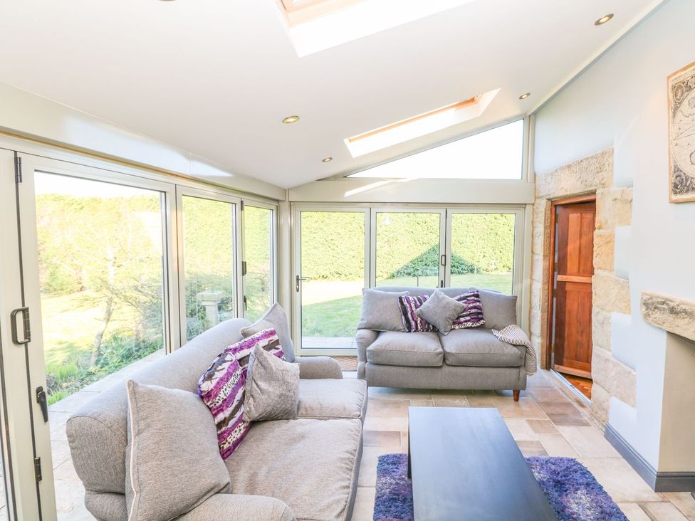 A conservatory with sofas and a table at Peters Lea in Bakewell