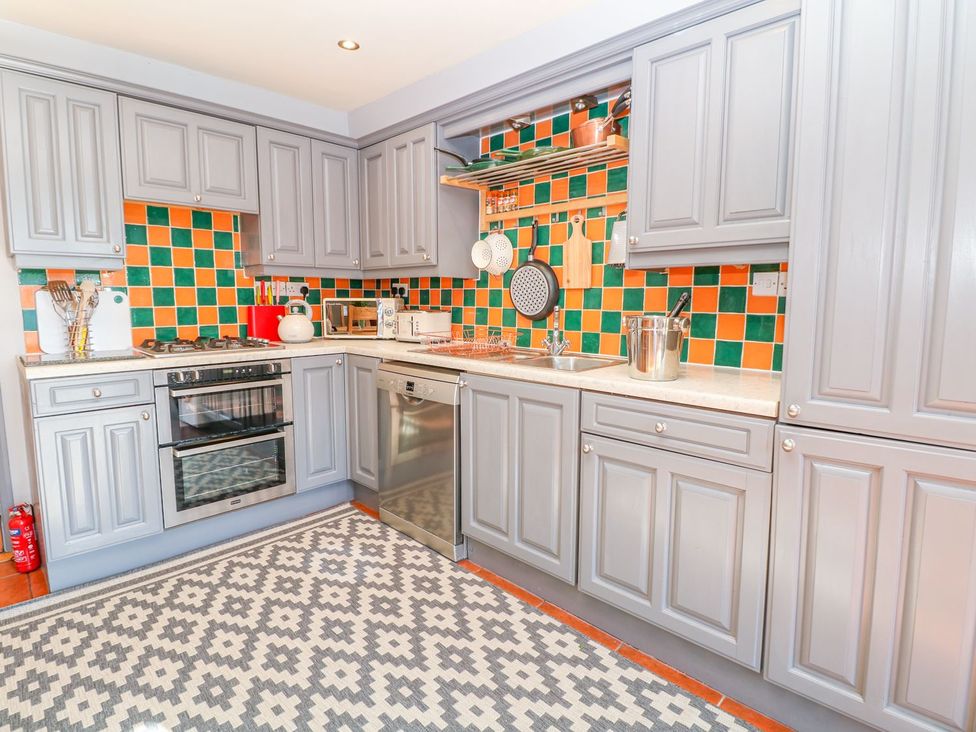 A kitchen with gray cabinets and orange and green tiles at Peters Lea in Bakewell