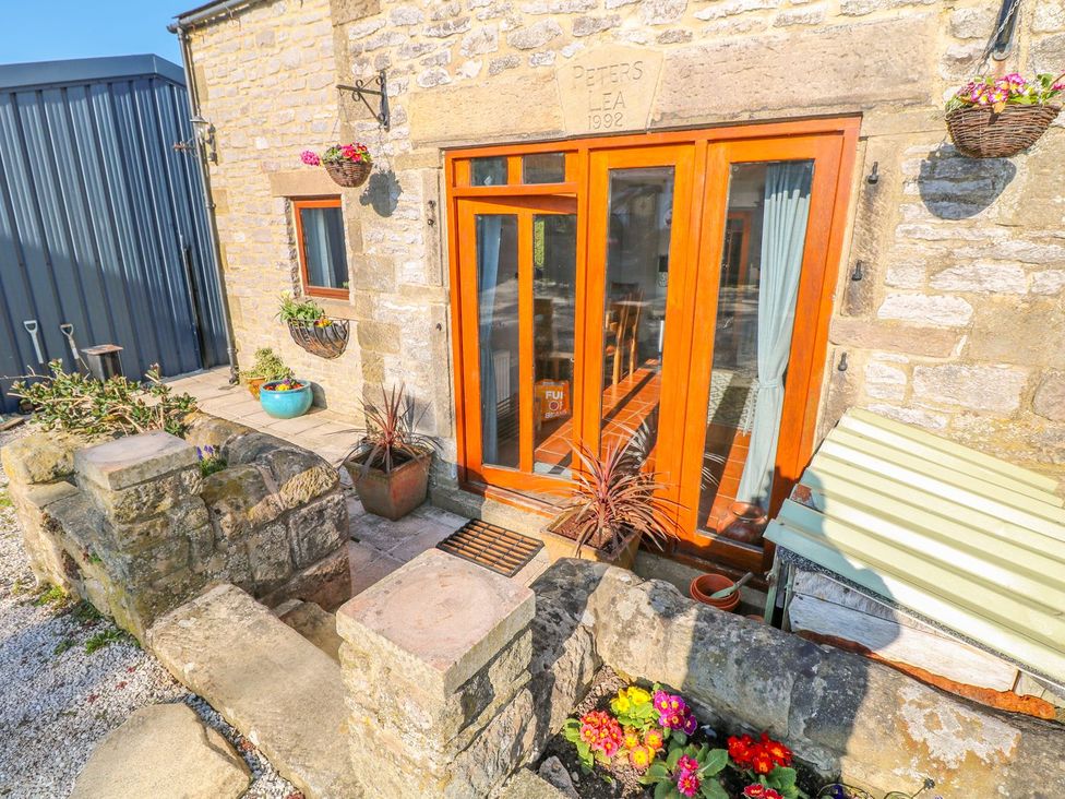 An outdoor entrance with flowers and stone features at Peters Lea in Bakewell