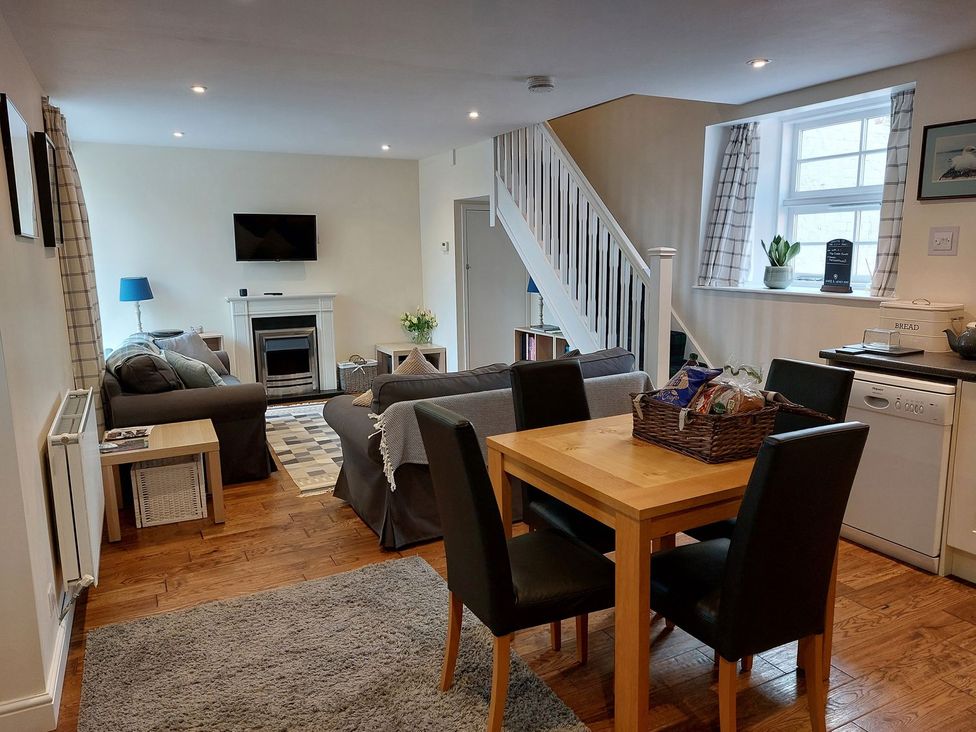 A living room with a sofa and dining area at The Coach House- Canonbie near Langholm