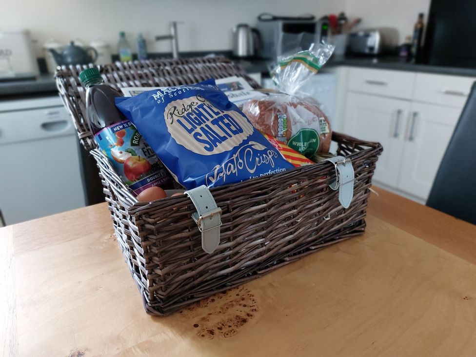 A wicker basket containing snacks and drinks in a kitchen at The Coach House- Canonbie near Langholm