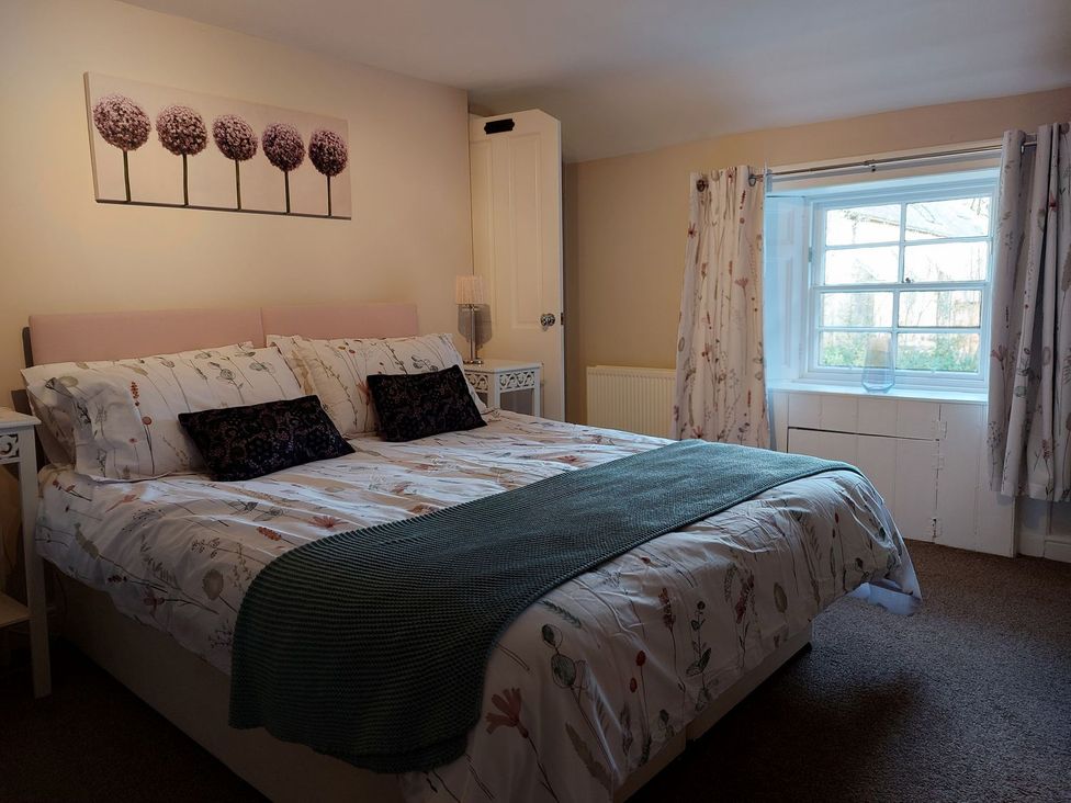 A bedroom with a double bed and bedside table at The Coach House- Canonbie near Langholm