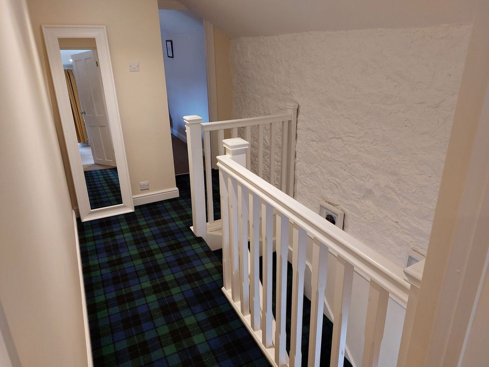 A hallway with a staircase and a mirror at The Coach House- Canonbie near Langholm