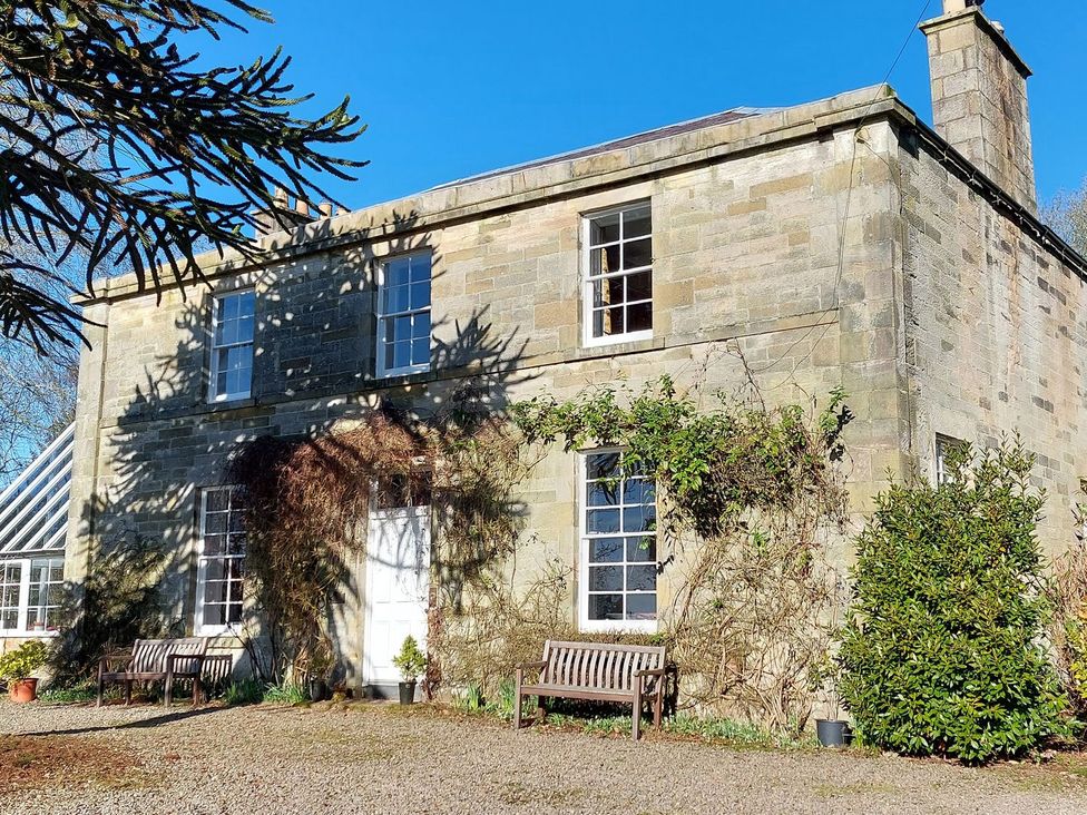A house with benches and plants outside at The Coach House- Canonbie near Langholm