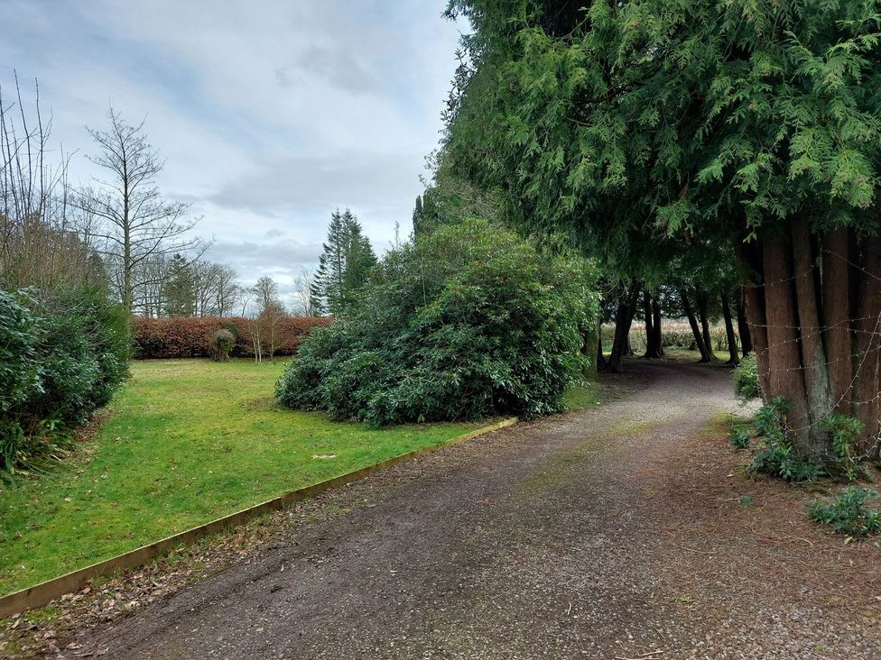 A garden with a gravel pathway and trees at The Coach House- Canonbie, Canonbie near Langholm