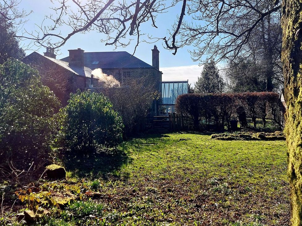 A house with a garden and smoke coming from the chimney at The Coach House- Canonbie near Langholm