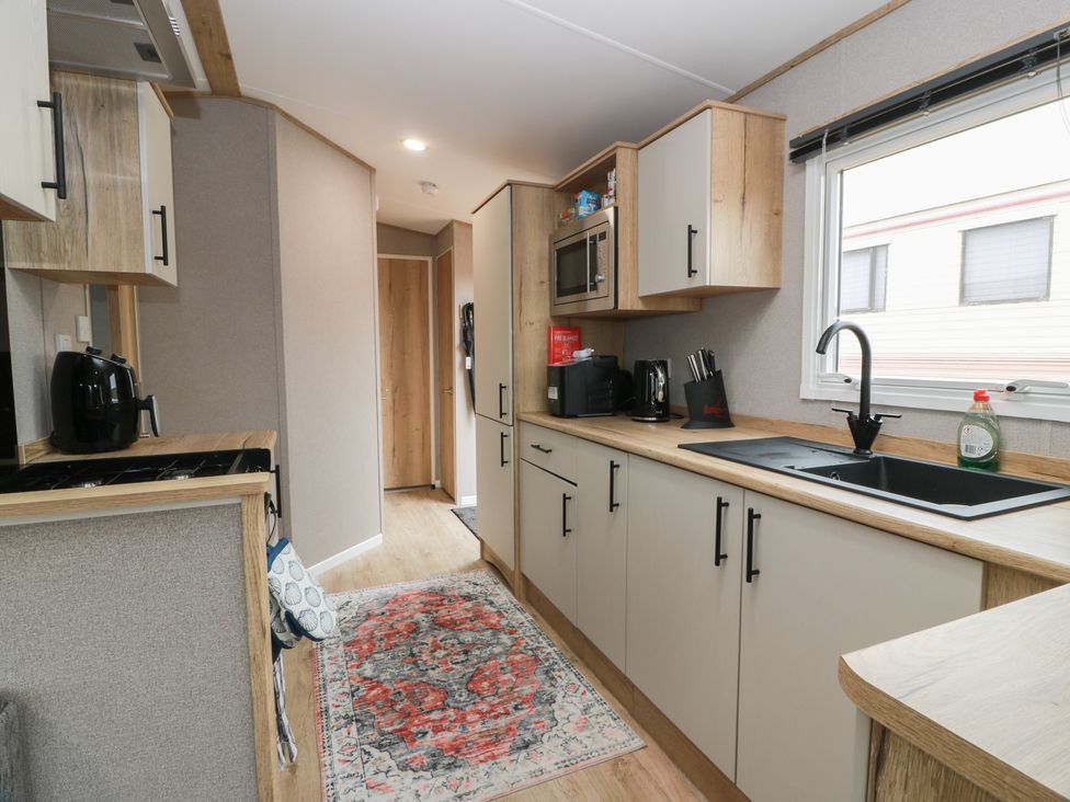 A kitchen with cabinets, a sink and appliances at Ellies House in Stranraer
