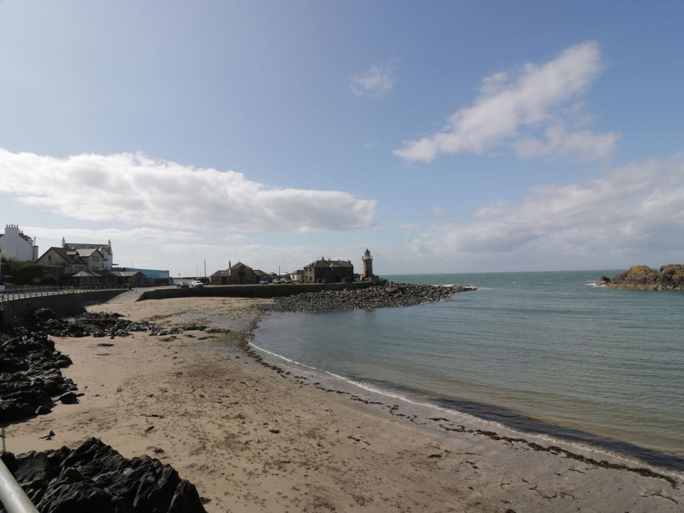 A beach with a lighthouse and houses at Ellies House in Stranraer