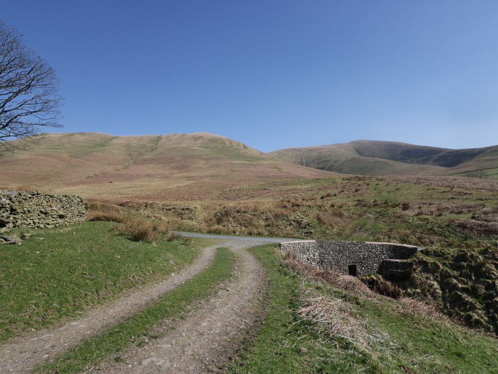 A road leading to a stone building near mountains at Castle Terrace Penrith