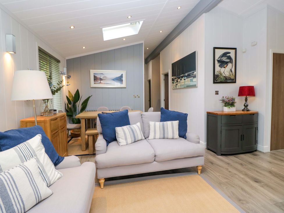 A living room with a sofa and dining table at 5 Waterside Wood Troutbeck Bridge