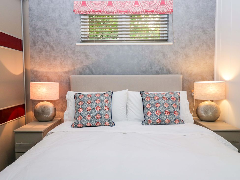 A bedroom with a bed and bedside tables at 5 Waterside Wood in Troutbeck Bridge