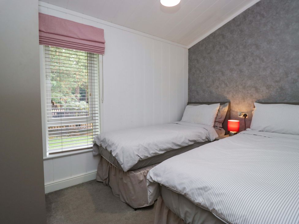 A bedroom with two beds and a window at 5 Waterside Wood in Troutbeck Bridge