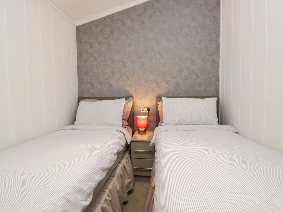 A bedroom with two single beds and a lamp at 5 Waterside Wood Troutbeck Bridge
