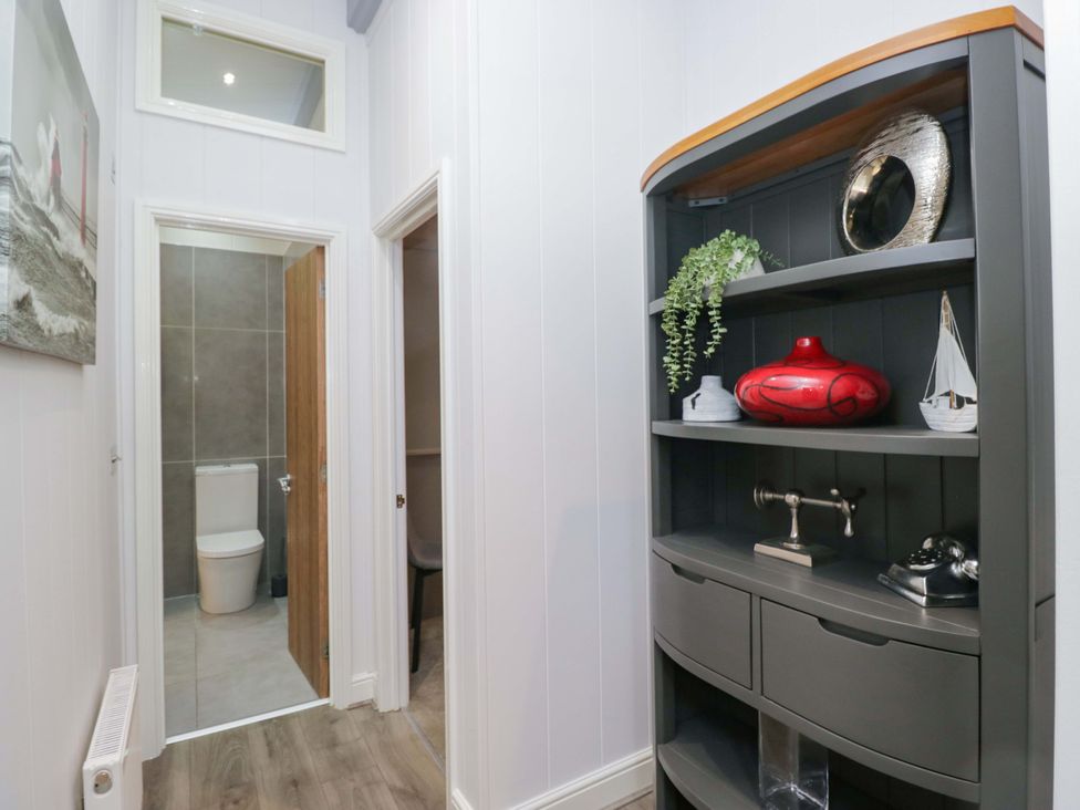 A hallway with a shelf and a view of a bathroom at 5 Waterside Wood Troutbeck Bridge