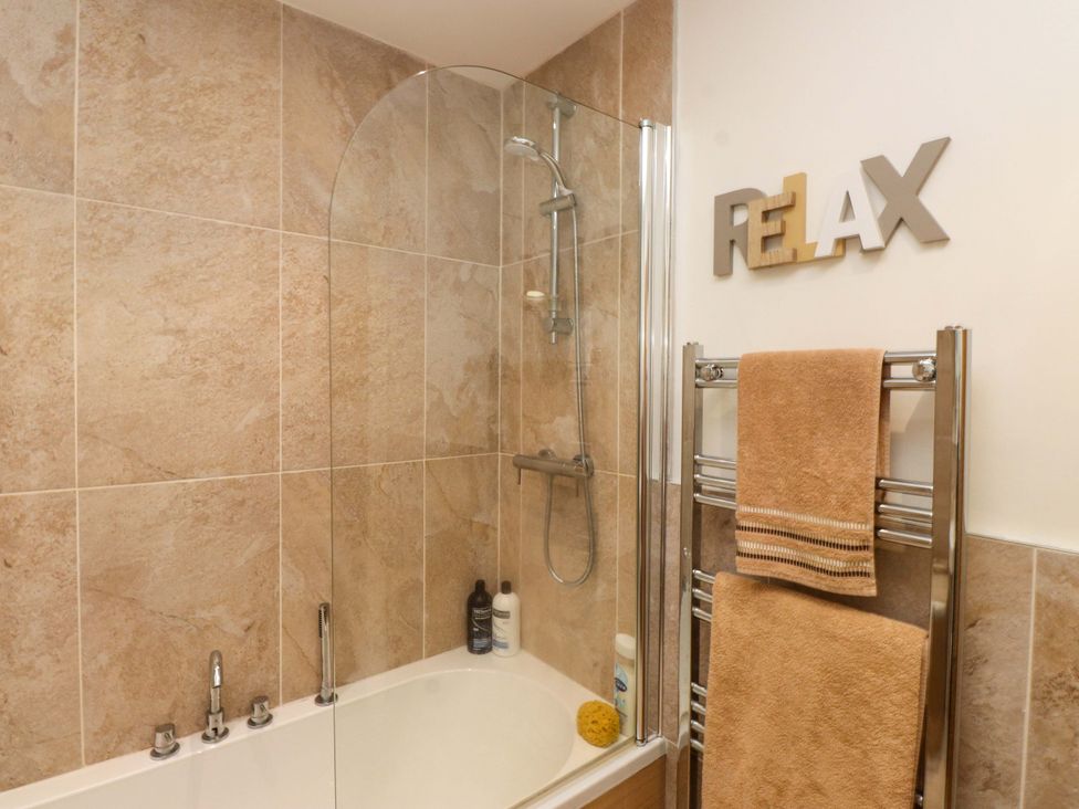A bathroom with a shower and bathtub at Heulfan in Conwy