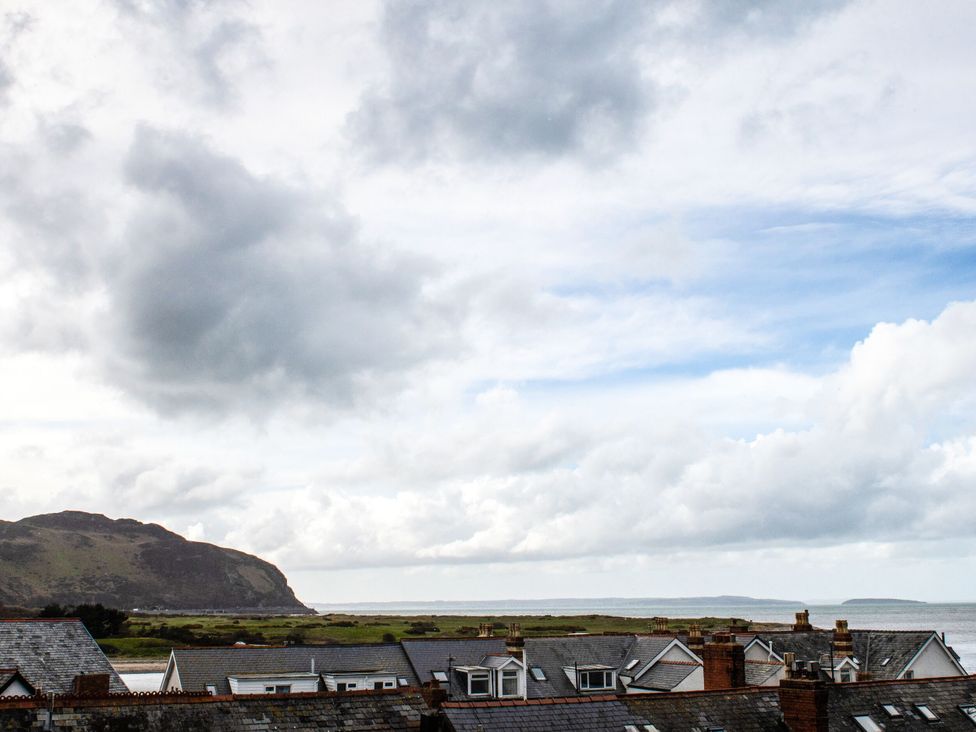 A view of rooftops and the sea under a cloudy sky at Heulfan Conwy