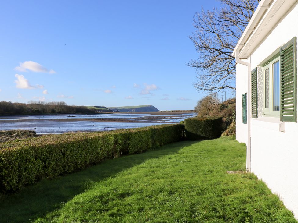 A garden with a hedge and view of a river at Bryncyn in Newport, Pembrokeshire